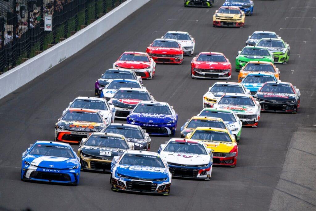 Cars jockey for position as they head into the first turn after a restart Sunday, July 27, 2025, during the Brickyard 400 at Indianapolis Motor Speedway.
