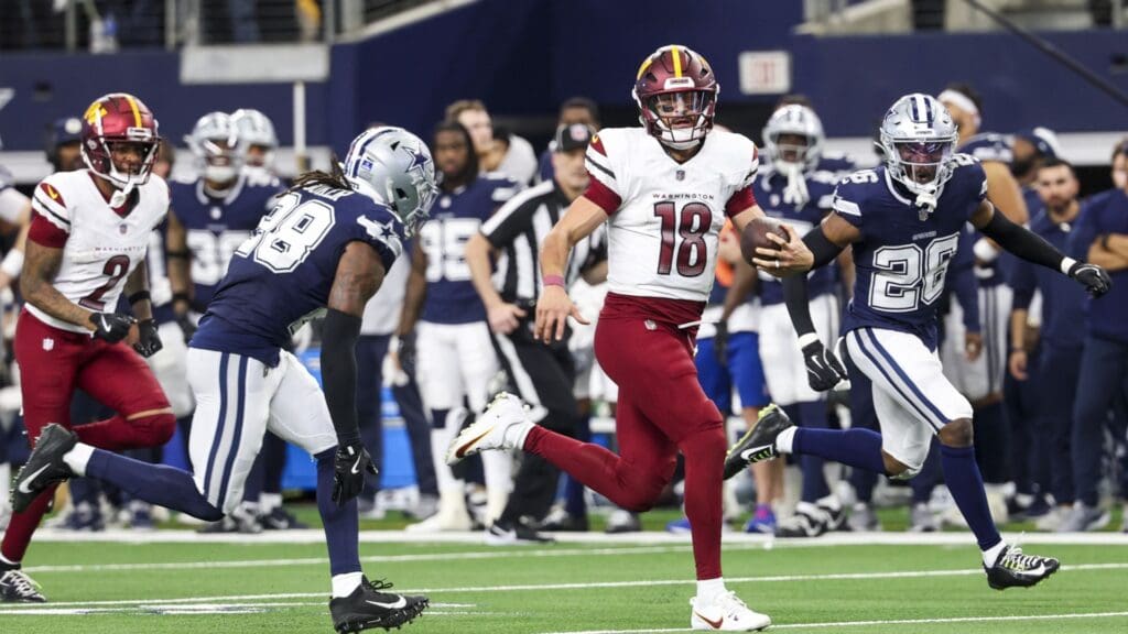 Jan 5, 2025; Arlington, Texas, USA; Washington Commanders quarterback Marcus Mariota (18) run past Dallas Cowboys safety Malik Hooker (28) during the fourth quarter at AT&T Stadium.